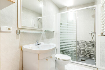 Toilet with white cabinets, shower with screen and white wall radiator