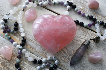 A top view image of a rose quartz crystal heart with a meditation mala necklace. 