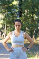 vertical portrait of a young sporty girl with an angry expression and arms around her waist.