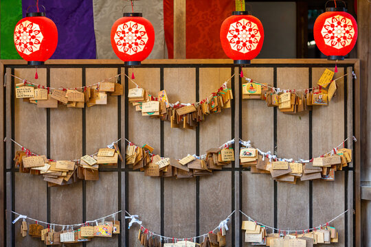 emas hanged and displayed on the wooden wall with traditional red lanterns in shinto shrine