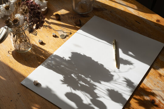 White Paper Sheet With Golden Pen On A Wooden Table With Flowers And Vintage Elements. 