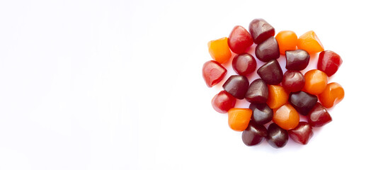 Close-up texture of red, orange and purple multivitamin gummies on white background. Healthy...