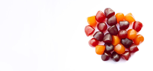 Obraz premium Close-up texture of red, orange and purple multivitamin gummies on white background. Healthy lifestyle concept