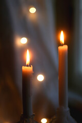 Two lit candles at night. Bokeh lights in the background. Selective focus.