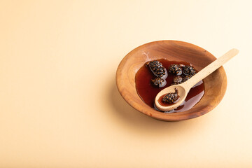 Pine cone jam on orange pastel background, side view, copy space.