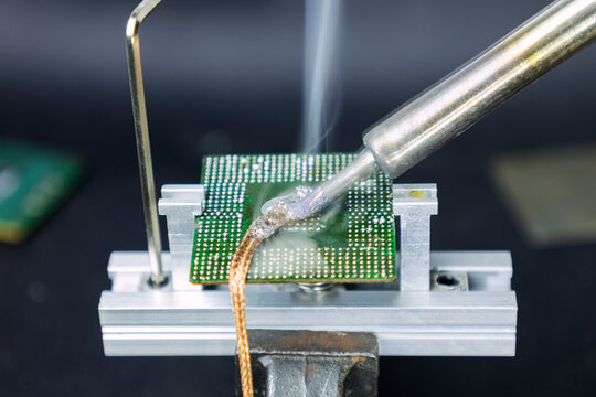 Soldering iron and copper wire to remove excess solder from the laptop processor