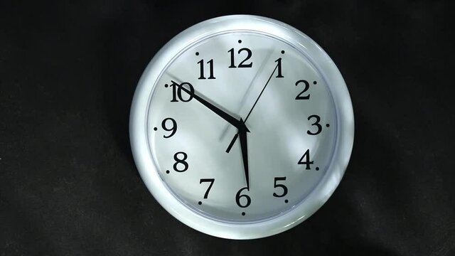 White clock on a black background. The second hand goes to 6 o'clock. Evening or morning.