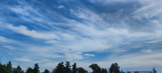 Cirrus clouds spread across the sky. The light blue sky is filled with high cirrus clouds with a...