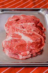Top quality fresh ribeye steak on a stainless steel tray and red and white stripe apron. Premium beef. Meat industry product. Butcher craft.