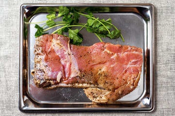 Raw pork belly slice with seasoning on a metal stainless steel tray. Meat industry product with fresh green coriander.