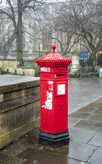 Fototapeta na wymiar Traditional red post box or letter box in the city of Norwich, Norfolk. Captured on a dull and foggy morning in late December