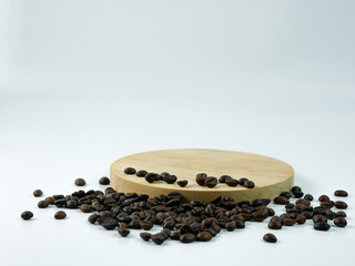 Coffee beans scattered on a round wooden plank isolated on a white background. Product placement...