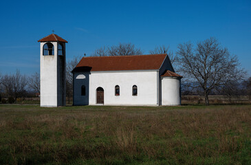 Fototapeta premium A view of a village church. The beautiful church yard with a huge meadow and a beautiful sky above. A lonely church waiting for people to stop by.