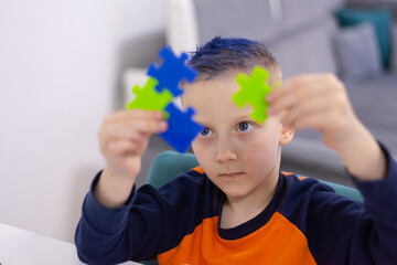 Little schoolboy holding puzzle pieces and trying to solve it