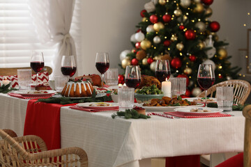 Festive dinner with delicious food and wine on table indoors. Christmas Eve celebration
