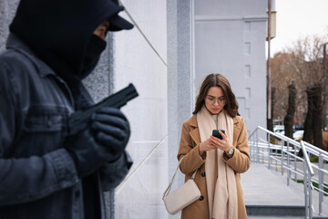 Criminal with gun hiding behind wall and waiting for woman on city street