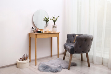 Stylish room interior with wooden dressing table and armchair