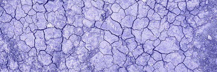 Dry cracked ground. Dried clay texture and patterns cracked surface of clay and land in color of year 2022. Banner.