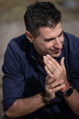 Close up portrait of a young classy businessman sitting alone near the Lisbon riverside. Elegant freelance architect sitting on the bench wearing a formal elegant blue shirt. Successful concept