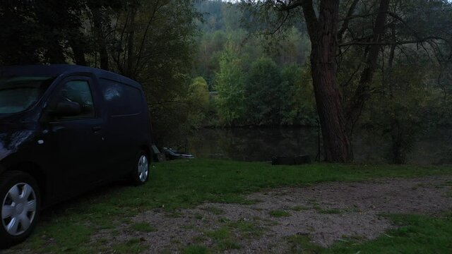 BLANKENBERG, GERMANY - Sep 25, 2021: A 4K footage with a dronefly of a Black car at the lake in autumn in the morning