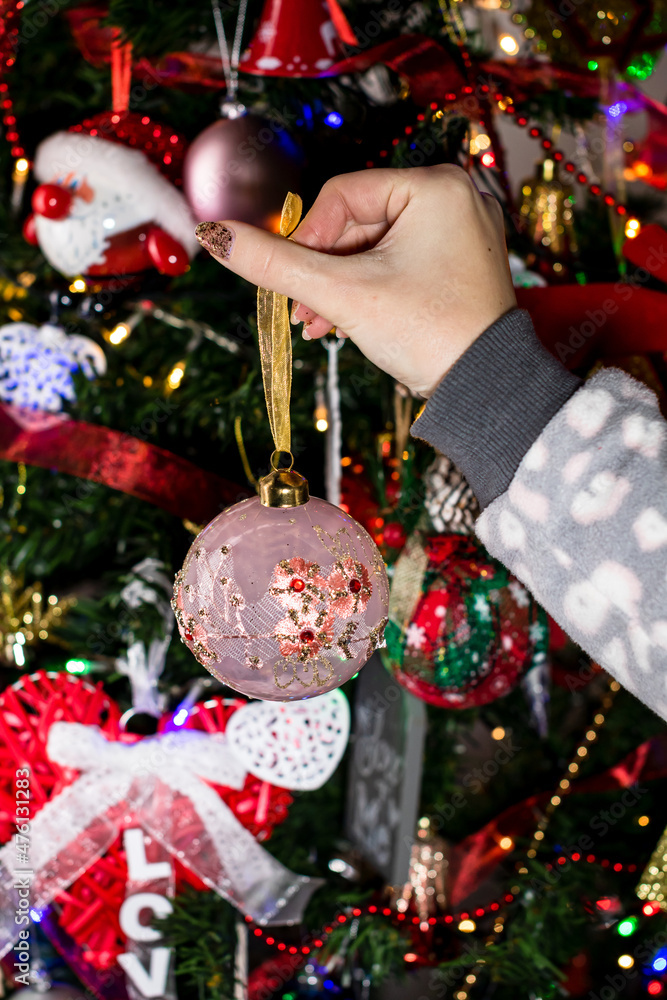 Canvas Prints Female hand hanging a Christmas decoration and ornament on the Christmas tree