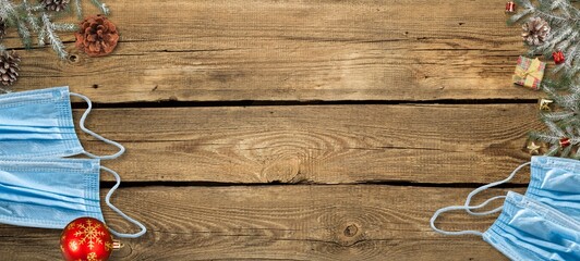 Christmas during COVID 19 pandemic concept with decorations, face masks over wood background.