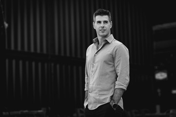 Success concept. Stylish young business man working as freelance architect in Lisbon is standing alone in front of the modern building in Portugal. Portrait of a classy man wearing elegant outfit