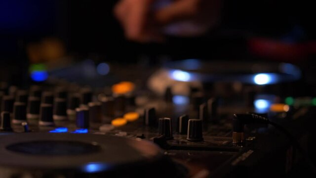 Close Up of DJ using Turntable and tweak some control panels on a dj's deck. Hands of DJ during Live Show in Concert Hall.
