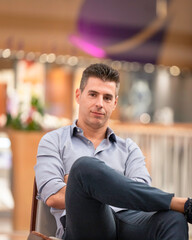 A young joyful business man posing for a portrait photograph inside an empty city mall in the heart of Lisbon, Portugal. Young attractive freelance architect wearing a classy shirt and formal outfit