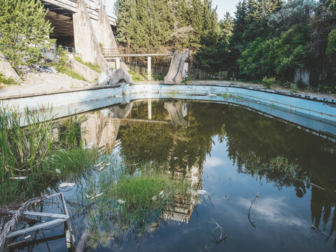 Russia, Sochi 15.06.2020. Old abandoned sanatorium outdoor pool with muddy water overgrown with reeds and full of rubbish