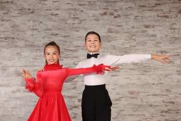 Beautifully dressed couple of kids dancing together in studio