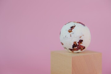 Bath bombs.Flower Bath Bombs with rose extract on wooden blocks on a pink background. Cosmetic bath...
