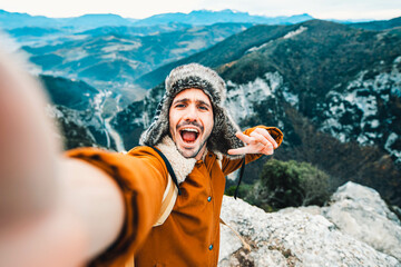 Hiker with backpack taking selfie on the top of the mountain - Happy man takes portrait picture...
