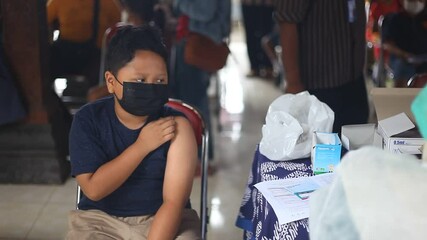 An elementary school boy is preparing for receiving the covid-19 vaccine