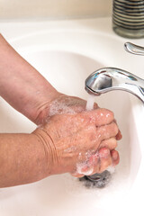  woman washing hands with soap over sink in bathroom, closeup.