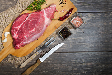 Raw meat on a wooden table with burlap and cutting board