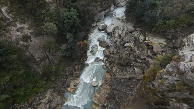 Flying over canyon looking down at the Marsyangdi River down past a cliff in Nepal.