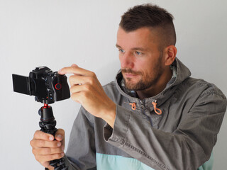 Man video blogger pushing button on mirrorless camera with mic, to start recording herself....