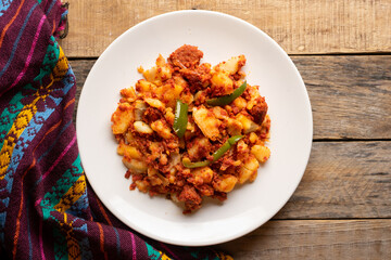 Potatoes with chorizo on a wooden background.  Mexican food