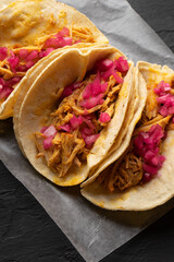 Pork meat tacos called cochinita pibil on a dark background. Mexican food