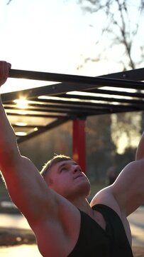 Muscular man doing pullups on sunset sky background. Calisthenics, healthy lifestyle and workout concept. vertical footage 