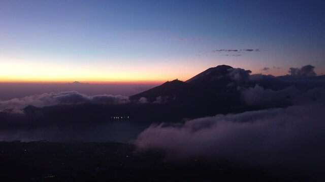 An aerial flying shot towards Mount Abang above clouds during sunset
