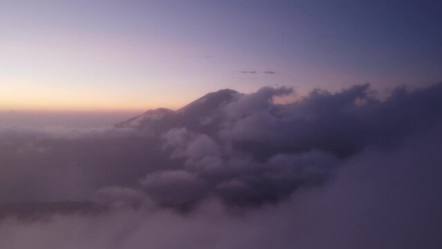 A Aerial flying shot towards Mount Abang above clouds during sunset