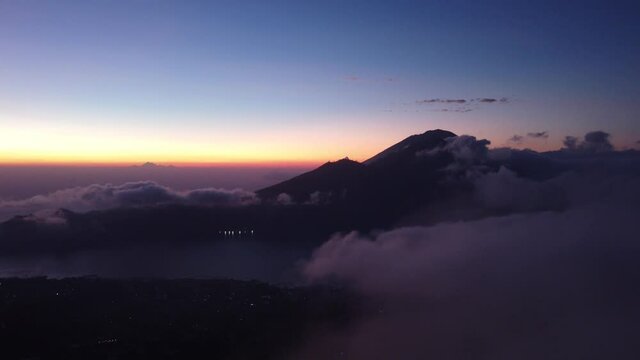 An Aerial flying shot towards Mount Abang above clouds during sunset