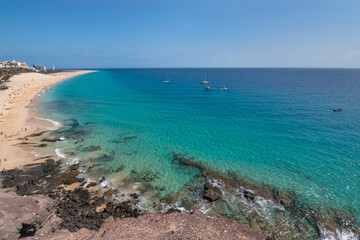 Fototapeta premium View of the beautiful and colorful Morro Jable Beach (Playa Morro Jable) from a viewpoint close by - Fuerteventura, Canary Islands, Spain