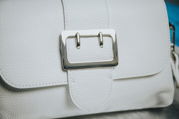 Closeup of a white leather handbag with a silver metal buckle