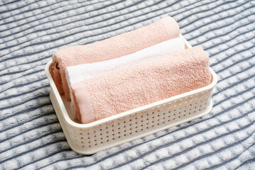 Plastic container with folded towels on gray background, organizing space.