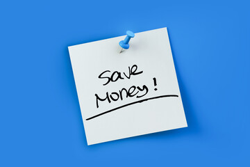 Save money written on white sticker note over blue background