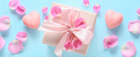 Composition with gift box for Valentine's Day and rose petals on color background