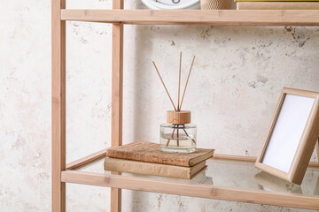 Wooden bookcase with reed diffuser and frame near light wall